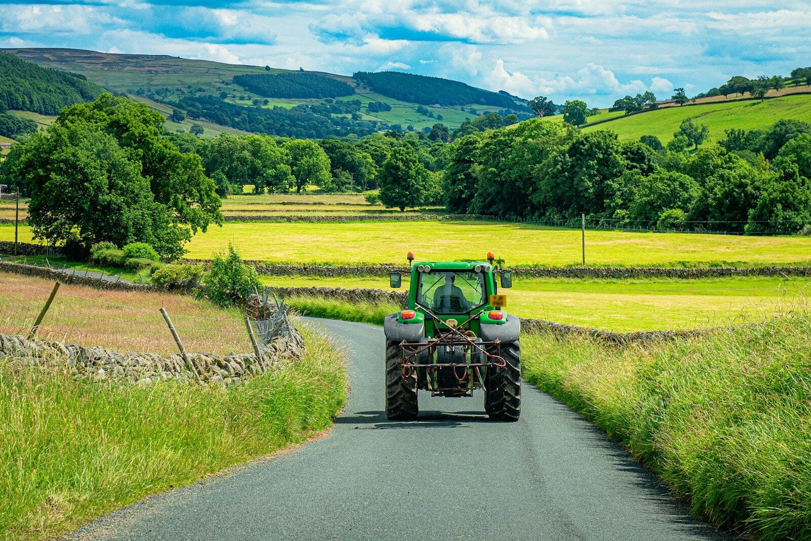 Green tractor drives down a rural road